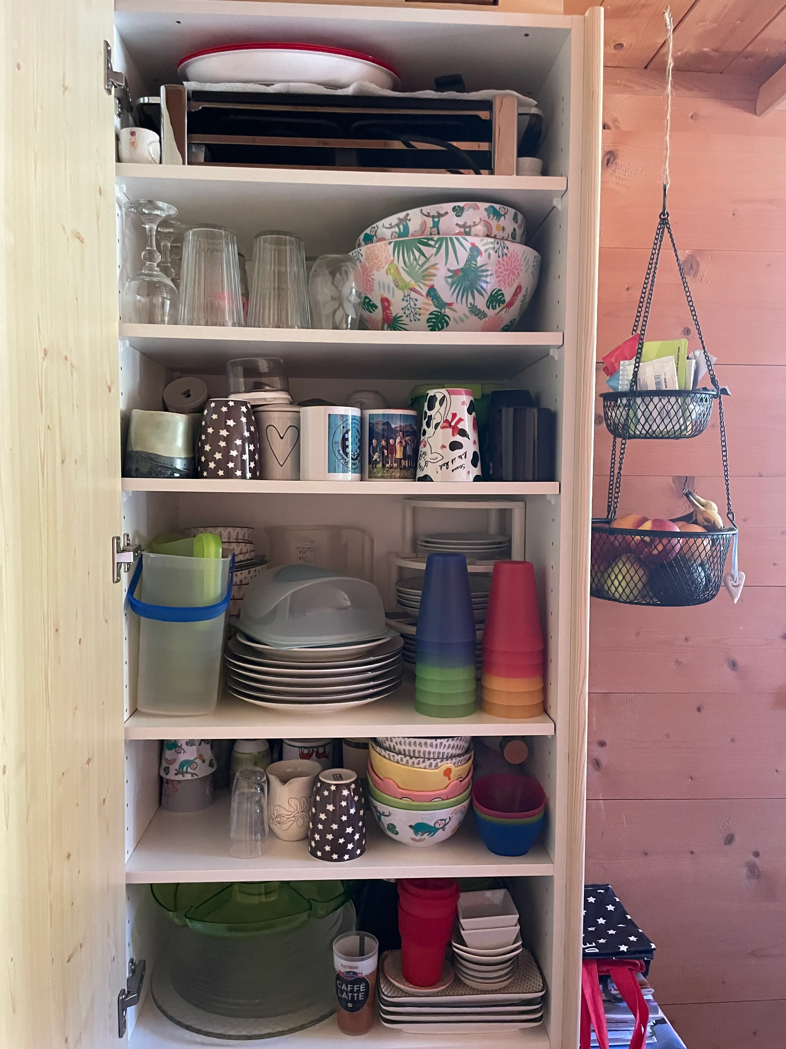 Offener Geschirrschrank, Fächer überfüllt.