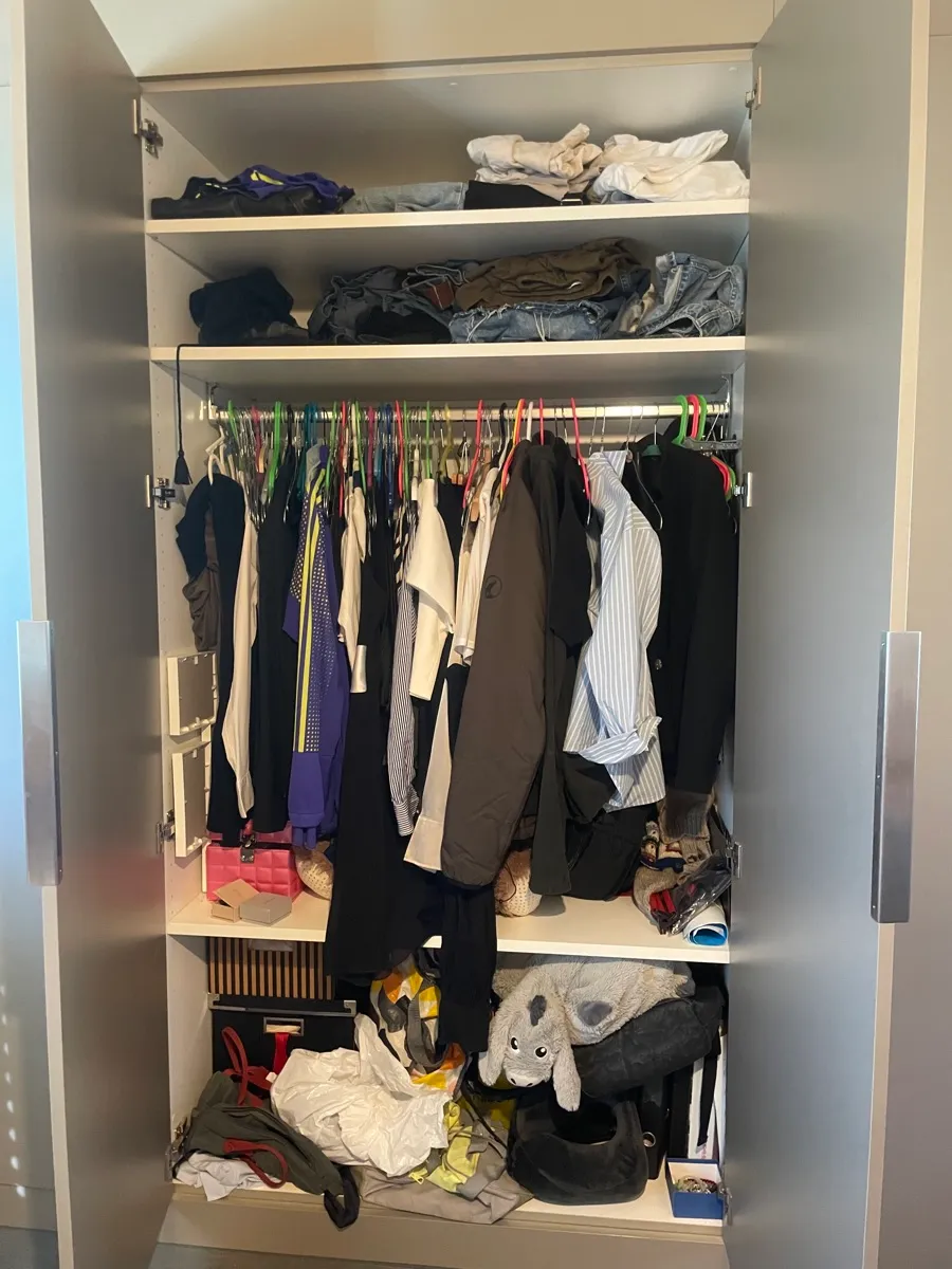 Offener grosser Kleiderschrank, Fächer überfüllt.